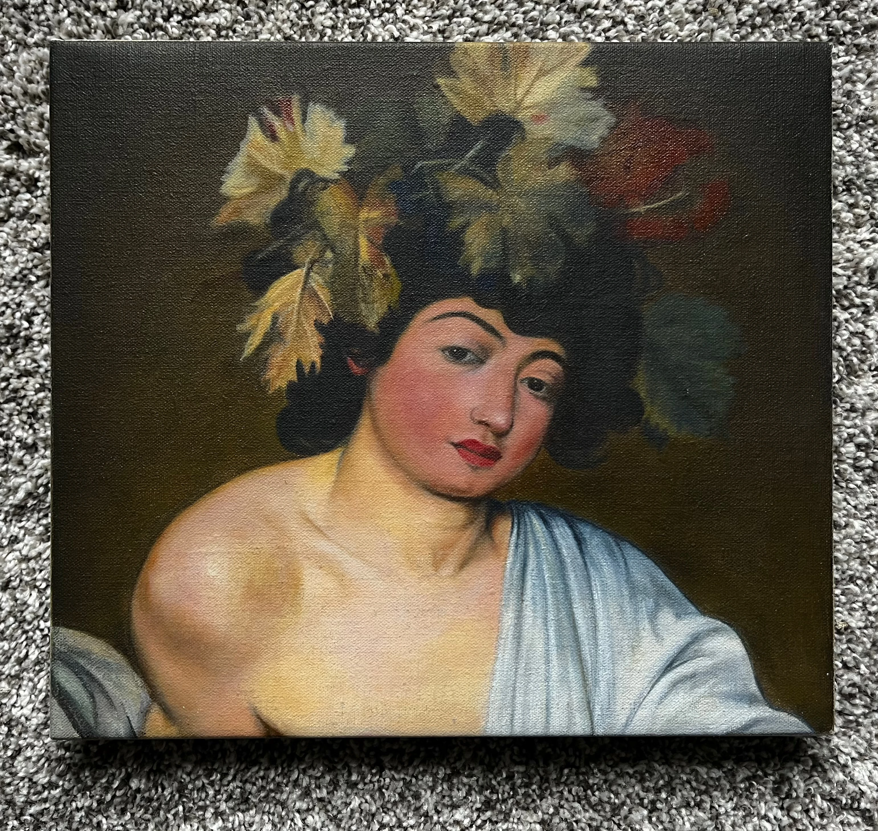 stretched oil painting, laying on grey carpet, of the god Bacchus with a headdress of leaves and fruit